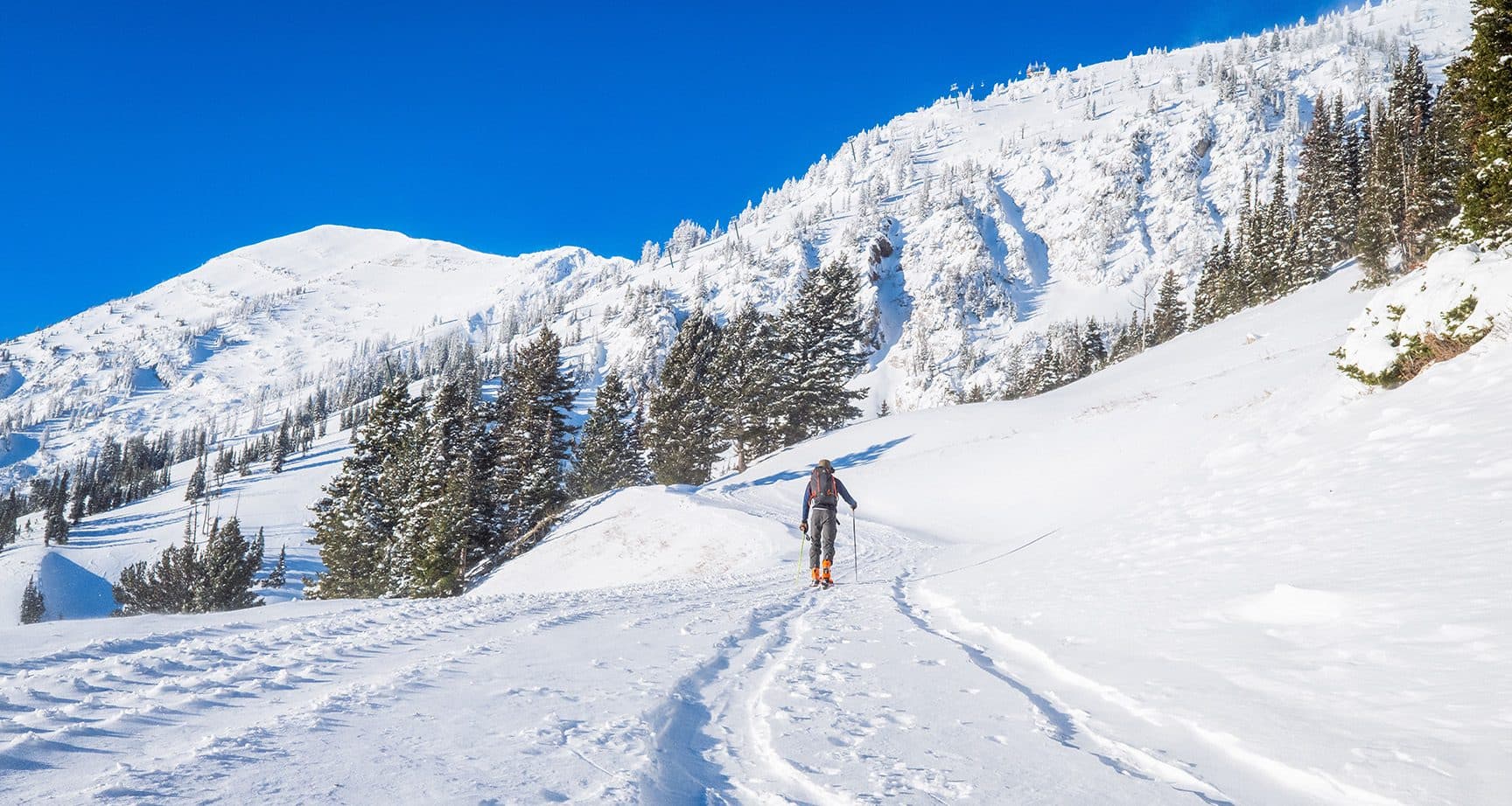 man uphill ski walking to mountains covered in snow